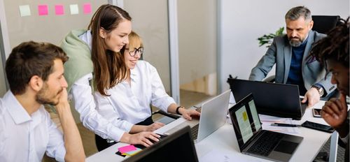 Groupe de collègues collaborant autour d'ordinateurs portables dans un bureau moderne et lumineux